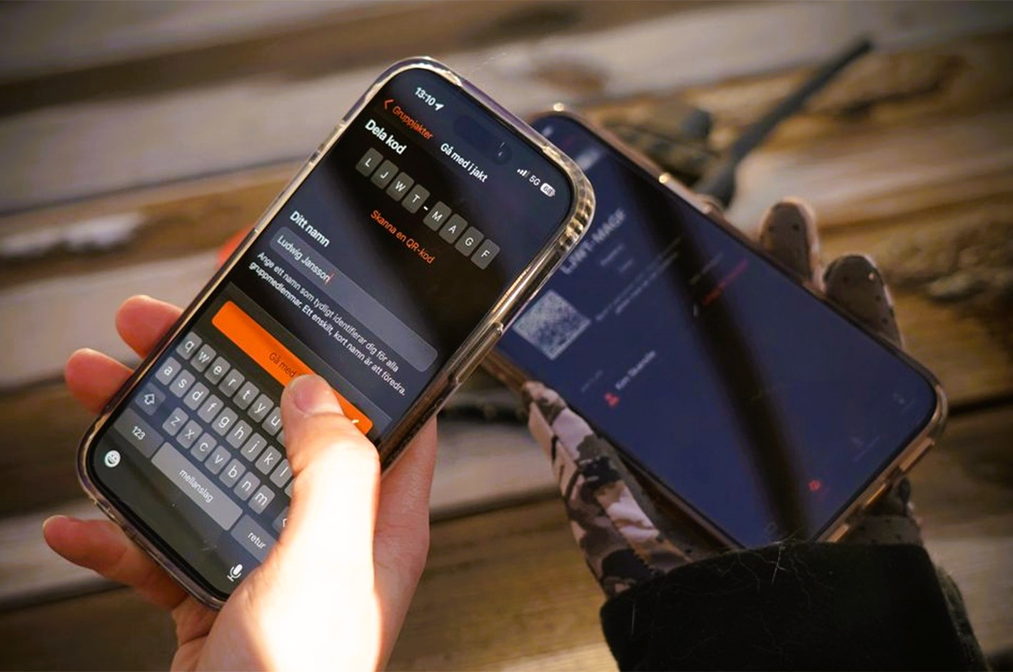 Garmin Alpha app på mobil viser jagtkort og positioner for gruppejagt i realtid på træbord.